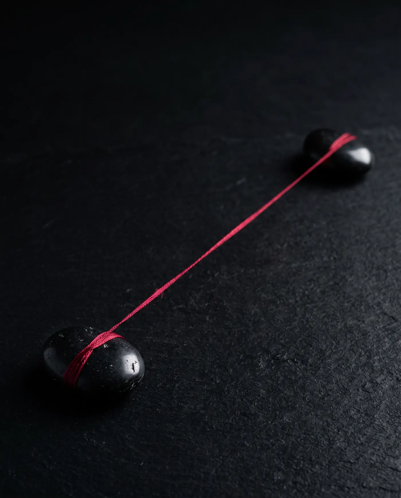 A red silk thread stretched between two black stones